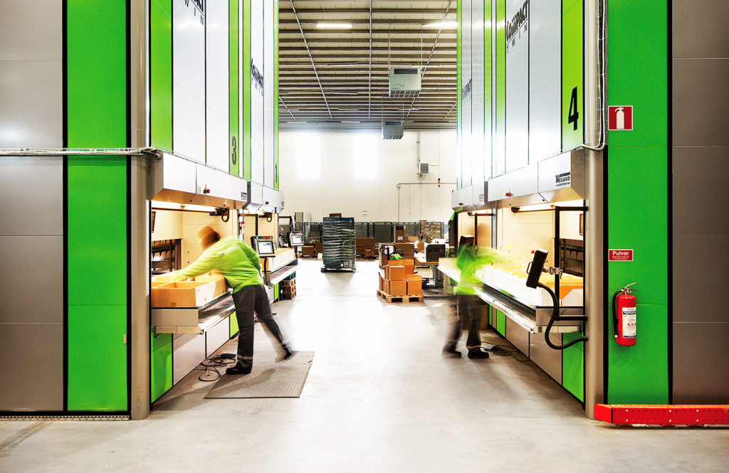 Illustrasjonsbilde fra lager med lagerautomater. To personer i fart jobber ved automatene. Foto.
